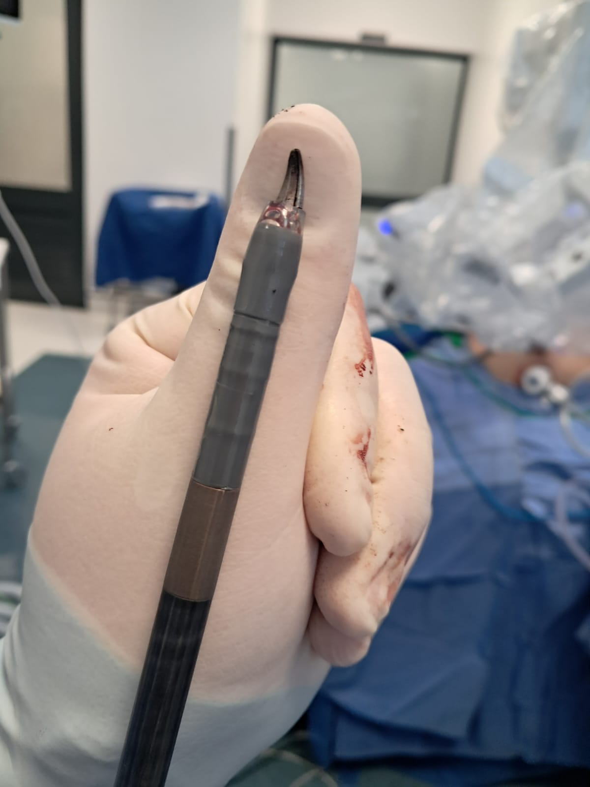 Close-up of a da Vinci EndoWrist instrument tip held between gloved fingers